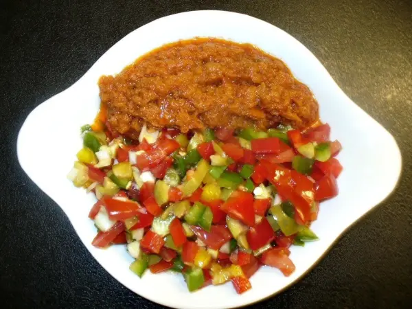 Ein Pesto-Putenschnitzel wird zusammen mit einem bunten, frischen Ofengemüse serviert, alles in einer weißen Schüssel.