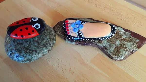 Eine handbemalte Steinformation zeigt einen Marienkäfer und einen Schuh, perfekt als kleines Geschenk in letzter Minute.