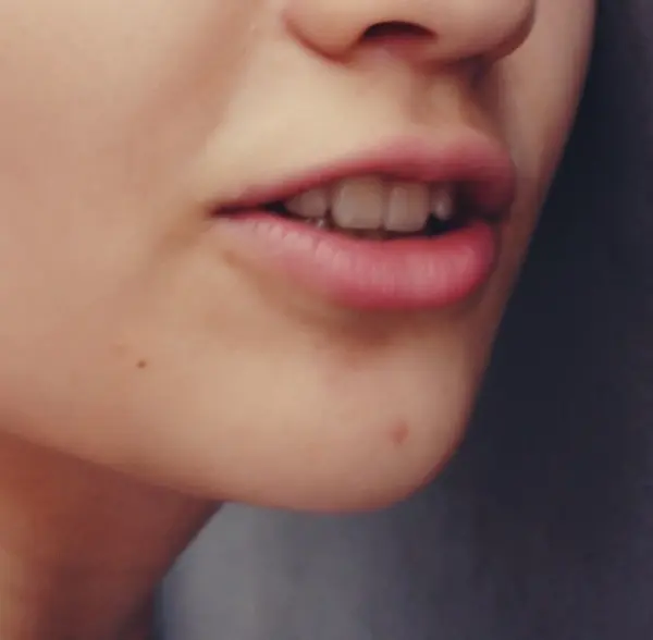Lippen mit leichtem Herpes sind im Vordergrund zu sehen, während der Hintergrund neutral und unscharf bleibt.