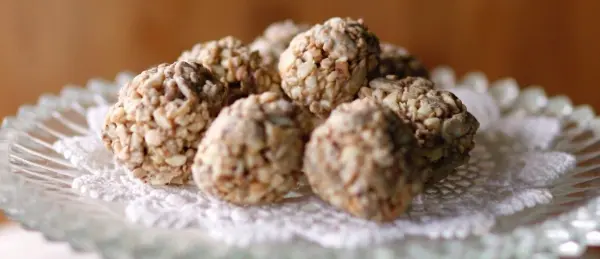 Müsli-Bällchen liegen auf einem eleganten Teller, umgeben von natürlichem Licht und einem rustikalen Hintergrund.