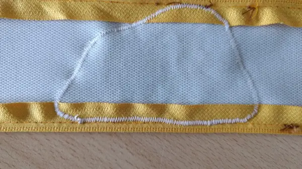 Eine gelbe und blaue Stofffläche zeigt eine aufgebrachte Vlieseline. Um das Kunstleder zu verstärken, wird Stoff bearbeitet.
