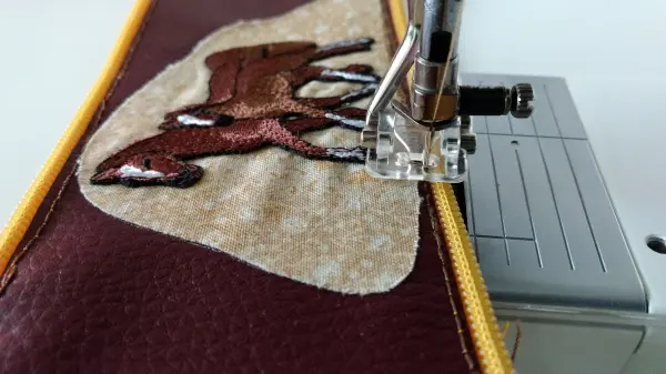 Ein farbiger Kunstlederpatch wird an einer Nähmaschine mit Vlieseline aufgebracht, um Stabilität und Design zu verbinden.