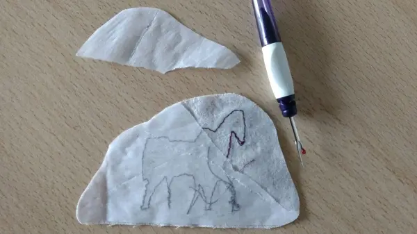 Ein Stoffstück mit einer Skizze eines Elefanten liegt auf einem Tisch, daneben ein Werkzeug zum Verzieren von Kunstleder.