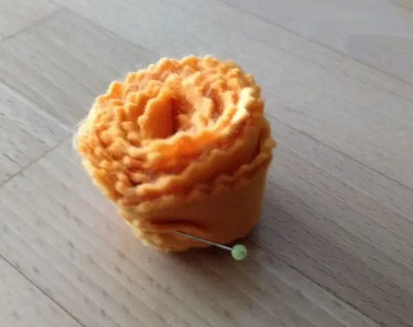Ein orangefarbener, spiralförmiger Osterkranz liegt auf einem hellen Tisch, bereit zum Verzehr oder Dekorieren.
