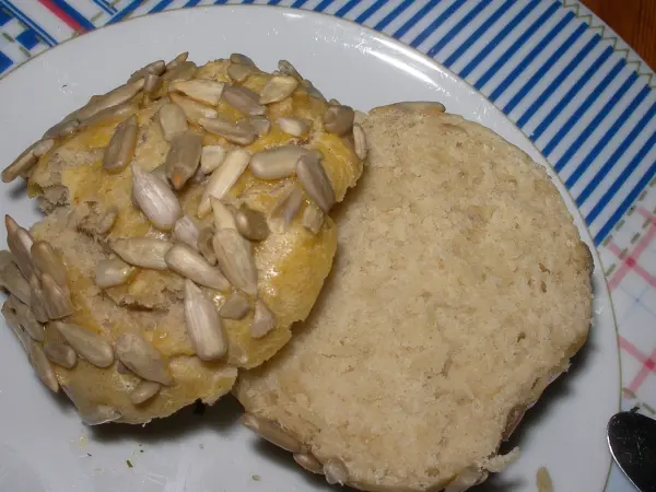 Schnelle Brötchen aus Backpulver-Hefe-Teig liegen auf einem Teller, die eine goldene Oberfläche mit Sonnenblumenkernen haben.