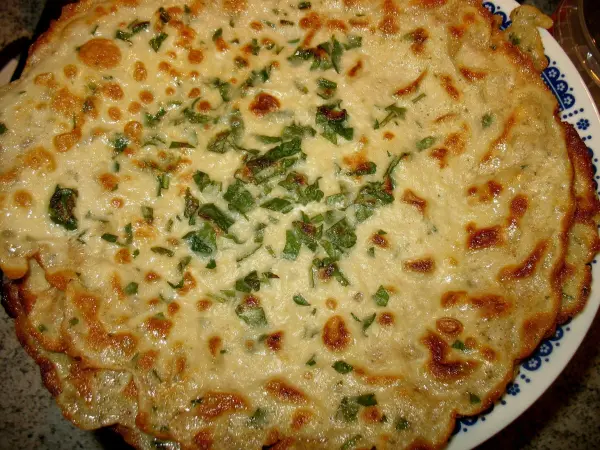 Überbackene Schinken-Spargel-Crepes, goldbraun und knusprig, liegen auf einem Teller, garniert mit frischen Kräutern.