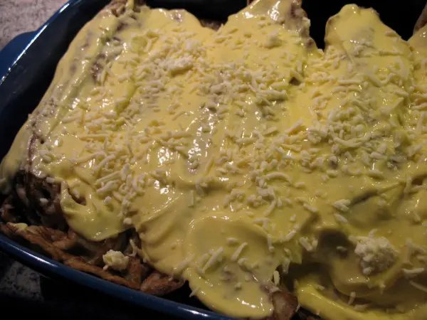 Überbackene Schinken-Spargel-Crepes sind in einer Auflaufform mit einer cremigen Käsesoße überzogen und goldbraun.