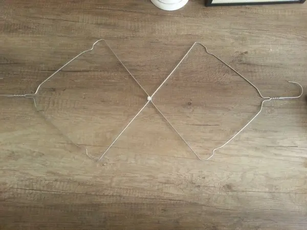 Ein Drahtkleiderbügel liegt auf einem Holzboden und ist so gestaltet, dass er platzsparend trocknen kann.