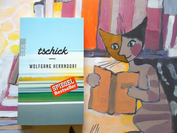 Ein Buchcover von "Tschick" zeigt den Titel und den Autor Wolfgang Herrndorf, umgeben von bunten, künstlerischen Hintergründen.