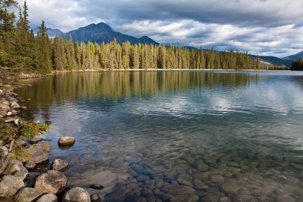 Ein ruhiger See spiegelt die umliegenden Bäume und Berge wider, ideal für besseres Fotografieren in der Natur.
