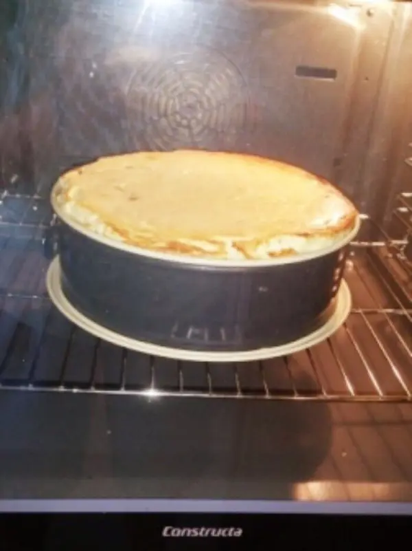 Ein Käsekuchen ohne Boden backt im Ofen, leicht goldbraun oben, während die Hitze gleichmäßig um ihn zirkuliert.