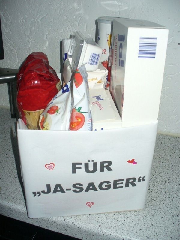 Ein Geschenkkorb, gefüllt mit verschiedenen Produkten, steht auf einer Arbeitsplatte, beschriftet mit "FÜR 'JA-SAGER'".
