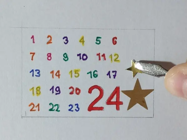 Ein bunter Adventskalender zeigt die Zahlen 1 bis 24, während eine Hand eine goldene Sternkarte bei Nummer 24 abhebt.