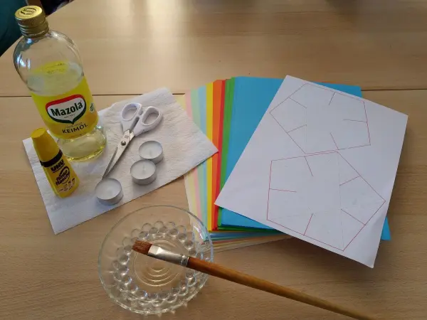 Papier-Windlichter basteln im Advent: Bastelmaterialien wie Papier, Schere und Farben liegen auf einem Tisch bereit.