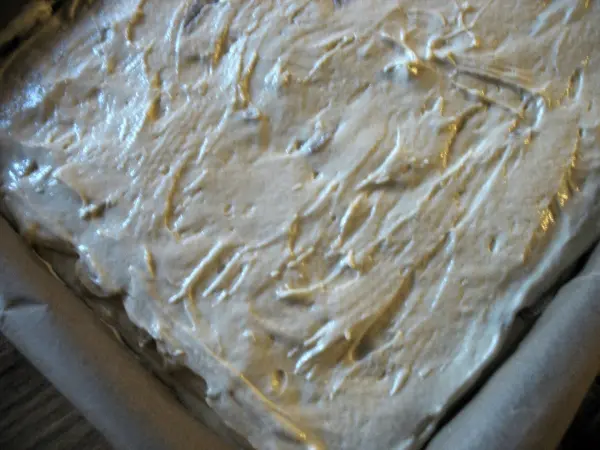 Ein Blechkuchen mit einer glatten, cremigen Oberfläche liegt in einer quadratischen Form, bereit zum Backen oder Servieren.