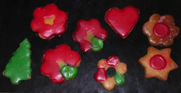 Bunte Weihnachtskekse in verschiedenen Formen liegen auf einem schwarzen Hintergrund, perfekt für festliche Teamarbeit und Verführung.