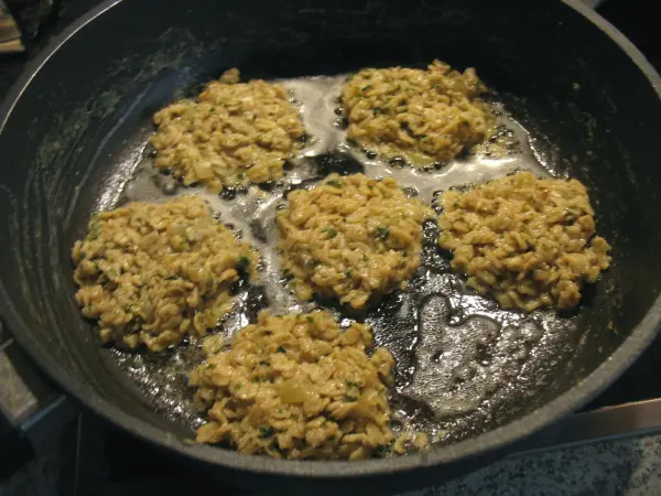 Die goldbraunen Haferflocken-Puffer braten in einer Pfanne mit heißem Öl und verbreiten einen köstlichen Duft in der Küche.