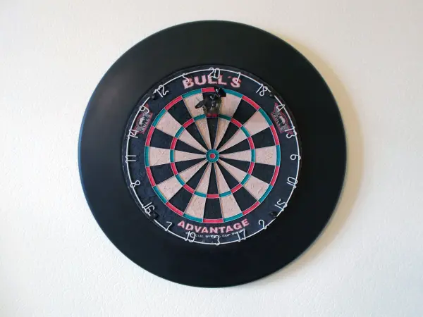 Ein Dartscheibe hängt an der Wand, bereit für ein Spiel, und zeigt das typische schwarz-weiße Feld mit dem Zielbereich.