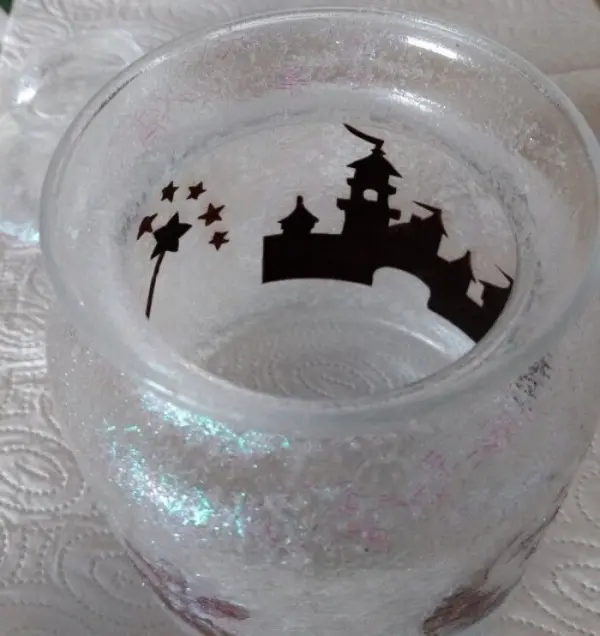 Ein schönes Windlicht "Fee im Glas" zeigt ein funkelndes Glas mit einer schwarzen Burgsilhouette und Sternen.
