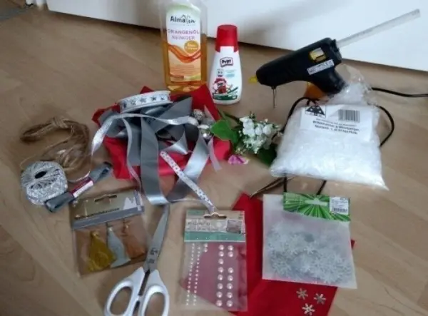 Ein Bastelset liegt auf einem Tisch: Bastelmaterialien wie Kleber, Scheren und verschiedene Bänder für das Windlicht.