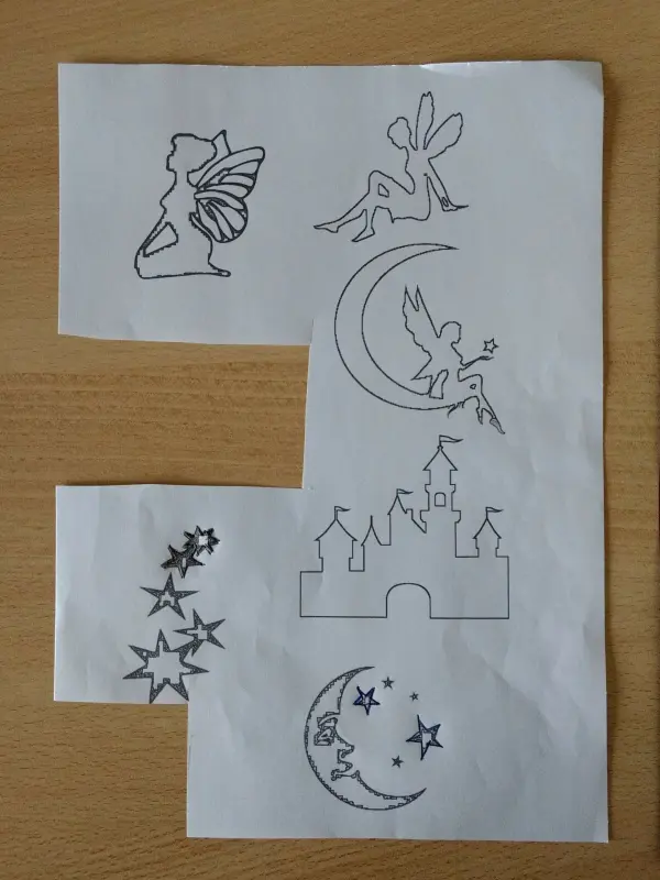 Papier mit Filzstiftzeichnungen von einer Fee, einem Mond, einem Schloss und Sternen ist bereit zum Basteln für ein Windlicht.