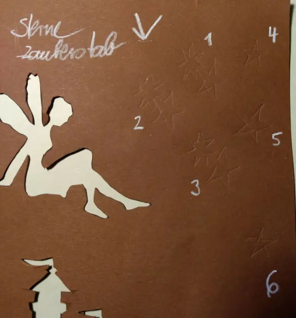 Ein Windlicht mit einer ausgeschnittenen Fee sitzt auf braunem Papier, während neben ihr Zahlen und Anweisungen vermerkt sind.