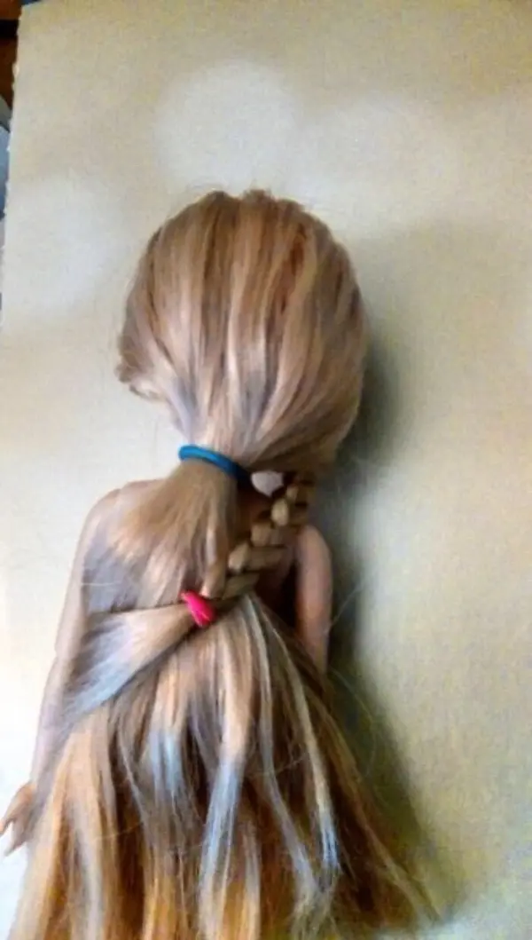 Eine Puppe mit langen Haaren hat Zopfgummis in verschiedenen Farben, die ihre Frisur halten und hübsch aussehen.
