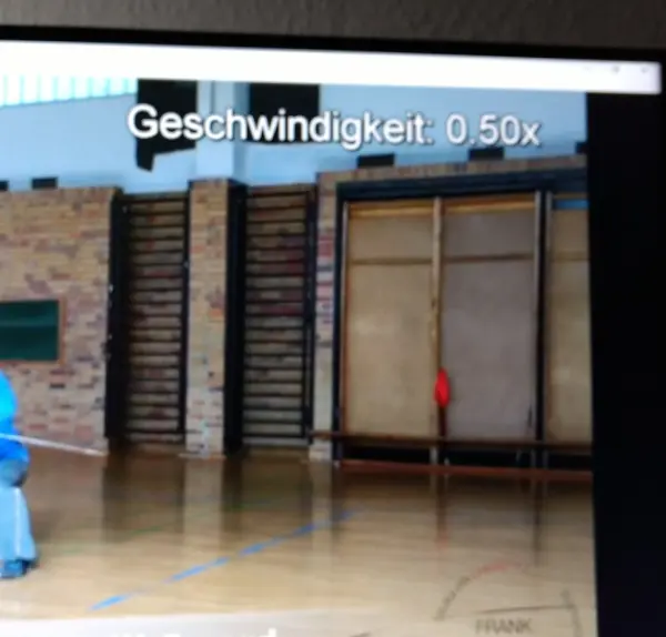 Ein Bildschirm zeigt einen Sporthallenbetrieb mit einer Geschwindigkeitsanzeige von 0,50x für langsames Abspielen.