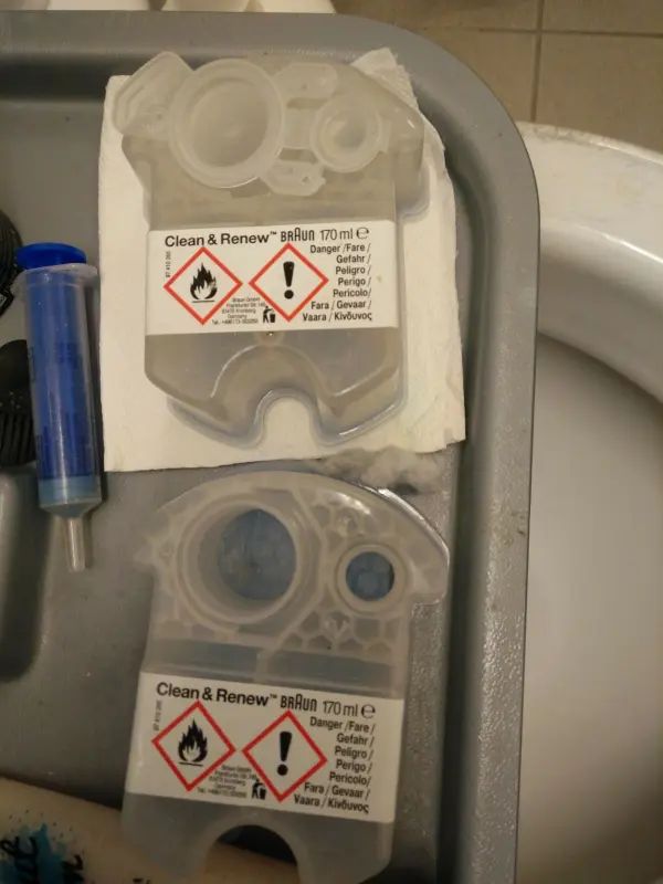 Transparente Reinigungskartuschen liegen auf einem Tablett und enthalten Warnhinweise für die sichere Anwendung im Badezimmer.
