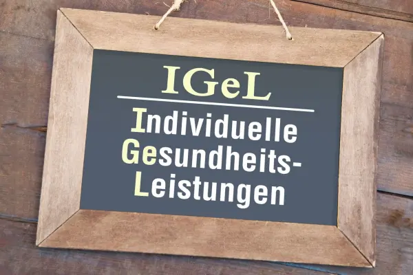 Ein Holzrahmen hält eine Tafel mit der Aufschrift "IGeL Individuelle Gesundheits-Leistungen", die über Gesundheitsleistungen informiert.