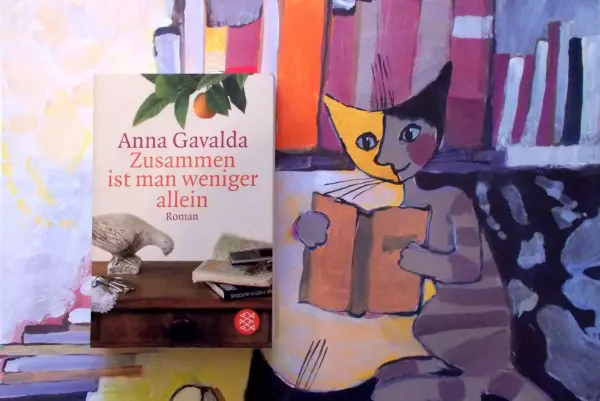 Das Buch "Zusammen ist man weniger allein" von Anna Gavalda liegt auf einem Tisch, umgeben von farbenfrohen Buchillustrationen.