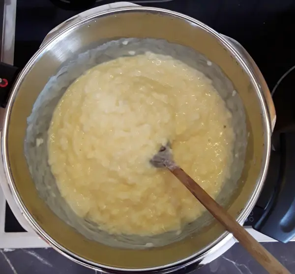 Cremiger Milchreis wird in einem Kochtopf mit einem Holzlöffel umgerührt, um die Konsistenz zu überprüfen und zu perfektionieren.