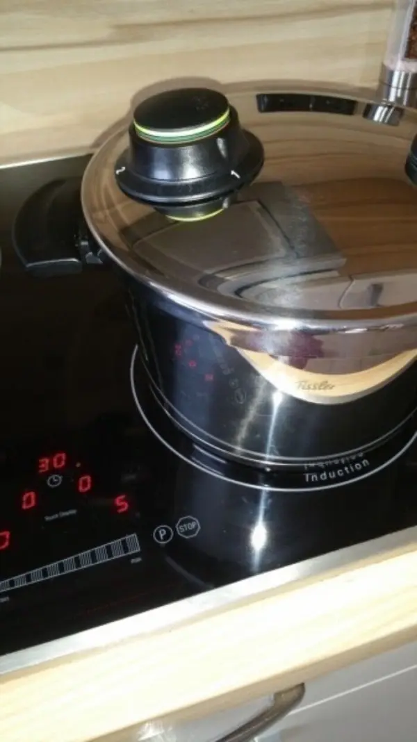 Ein Schnellkochtopf steht auf einer Induktionsherdplatte und kocht gefüllte Paprika bei 30 Grad. Der Deckel ist fest verschlossen.