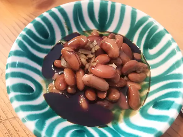 Ein Bohnensalat aus getrockneten Bohnen liegt in einer dekorativen Schüssel und zeigt die Bohnen in einer dunklen Marinade.