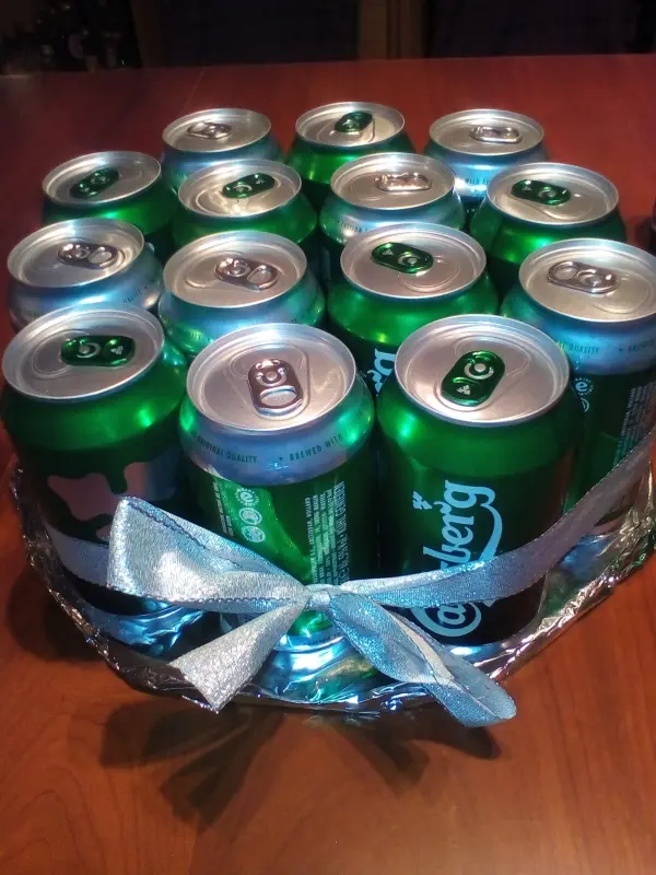 Eine festliche Biertorte aus Bierdosen steht auf einem Tisch, umgeben von einer gemütlichen Atmosphäre, ideal als Geschenkidee.