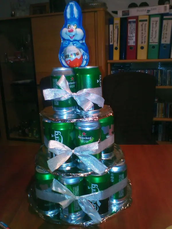 Eine mehrstöckige Biertorte aus grünen Dosen, dekoriert mit Bändern und einer kleinen Figur oben.
