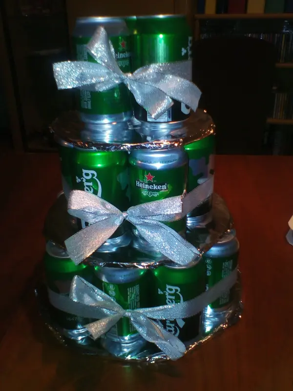 Auf einem Tisch steht eine kreative Biertorte aus grünen Getränkedosen, kunstvoll geschichtet und mit Schleifen verziert.
