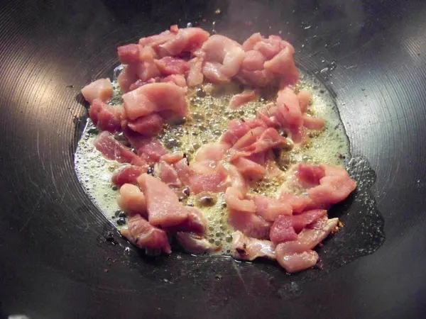 Zarte Stücke von Jiachang Doufu braten in einer Wokpfanne, umgeben von brizzelndem Fett und Dampf.