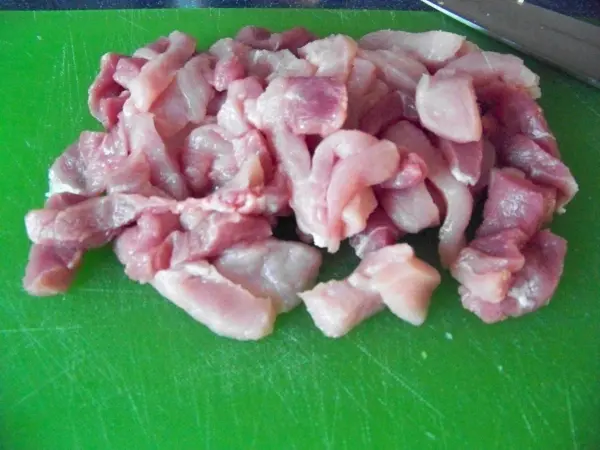 Saftige, gewürfelte Stücke von Fleisch liegen auf einem grünen Schneidebrett, bereit für die Zubereitung im Jiachang Doufu.