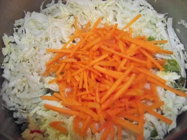 In einer Schüssel liegen frisch geschnittene Chinakohlstreifen und geraspelte Karotten, bereit für die Zubereitung der Suppe.
