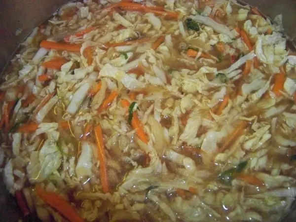 Eine dampfende Chinakohlsuppe mit zarten Gemüsestreifen in einer metallischen Schüssel, bereit zum Servieren.