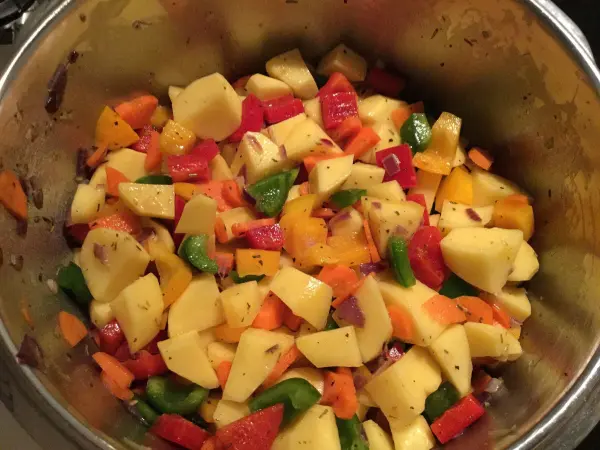 Bunte Kartoffeln und Paprika sind in einem Topf vermischt, während sie für ein köstliches Kartoffelgulasch zubereitet werden.