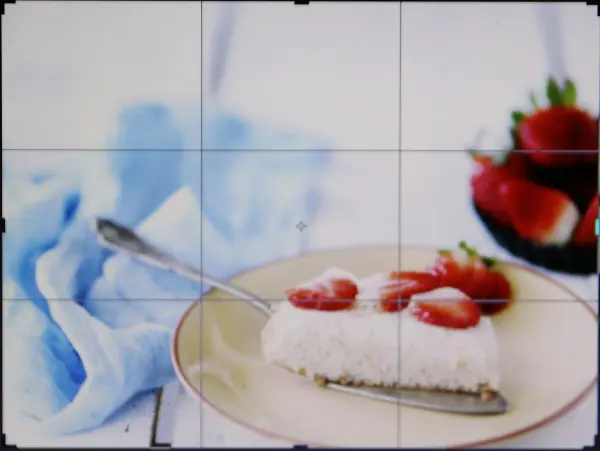 Ein Stück Kuchen mit Erdbeeren liegt auf einem Teller, während ein blauer Stoff im Hintergrund die Szene ergänzt.