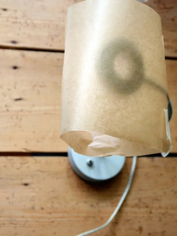 Eine Lampe mit einem laminierten Lampenschirm hängt über einem Holztisch und sorgt für warmes, einladendes Licht im Raum.
