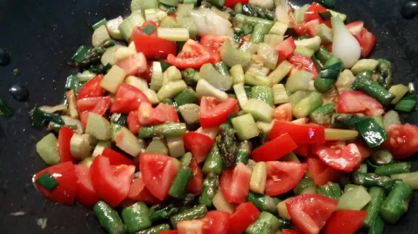 Ein farbenfroher Salat mit Spargel und Rhabarber wird zubereitet, umgeben von frischen, geschnittenen Zutaten.