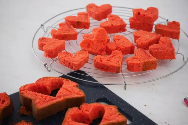Herzförmige Rührkuchen liegen auf einem Kuchengitter und warten darauf, verzehrt zu werden. Die leuchtend rote Farbe verleiht ihnen einen besonderen Charme.