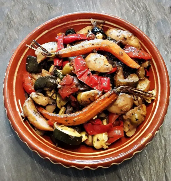 Ein bunter mediterraner Ofengemüse-Kartoffelsalat liegt auf einem rustikalen Teller und wird appetitlich präsentiert.