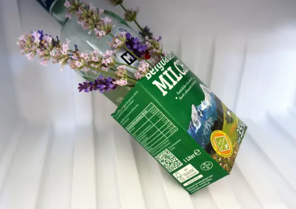 Ein Flaschenkühler aus Eis und Blumen ist in einem Kühlschrank platziert, um Getränke kühl zu halten. Die Blumen dekorieren die Flasche.