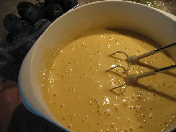 Ein cremiger Kuchenteig wird mit einem Handmixer in einer Schüssel zubereitet, um einen schnellen Obstkuchen vom Blech zu backen.