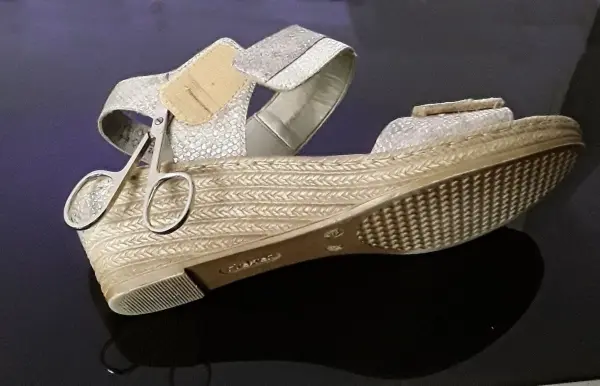 Ein eleganter Schuh mit Klettverschluss liegt auf einem glänzenden Tisch, umgeben von einem modernen, schlichten Raum.